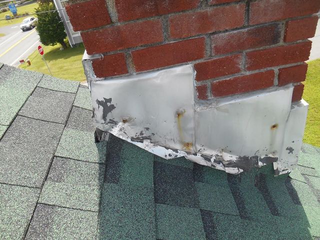 Bent, corroded flashing at the base of a chimney