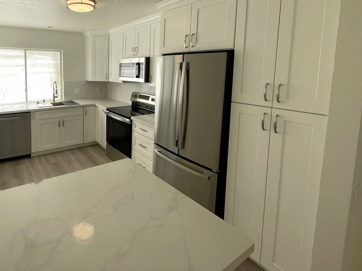 Kitchen with white shaker cabinets, quartz counters and stainless appliances
