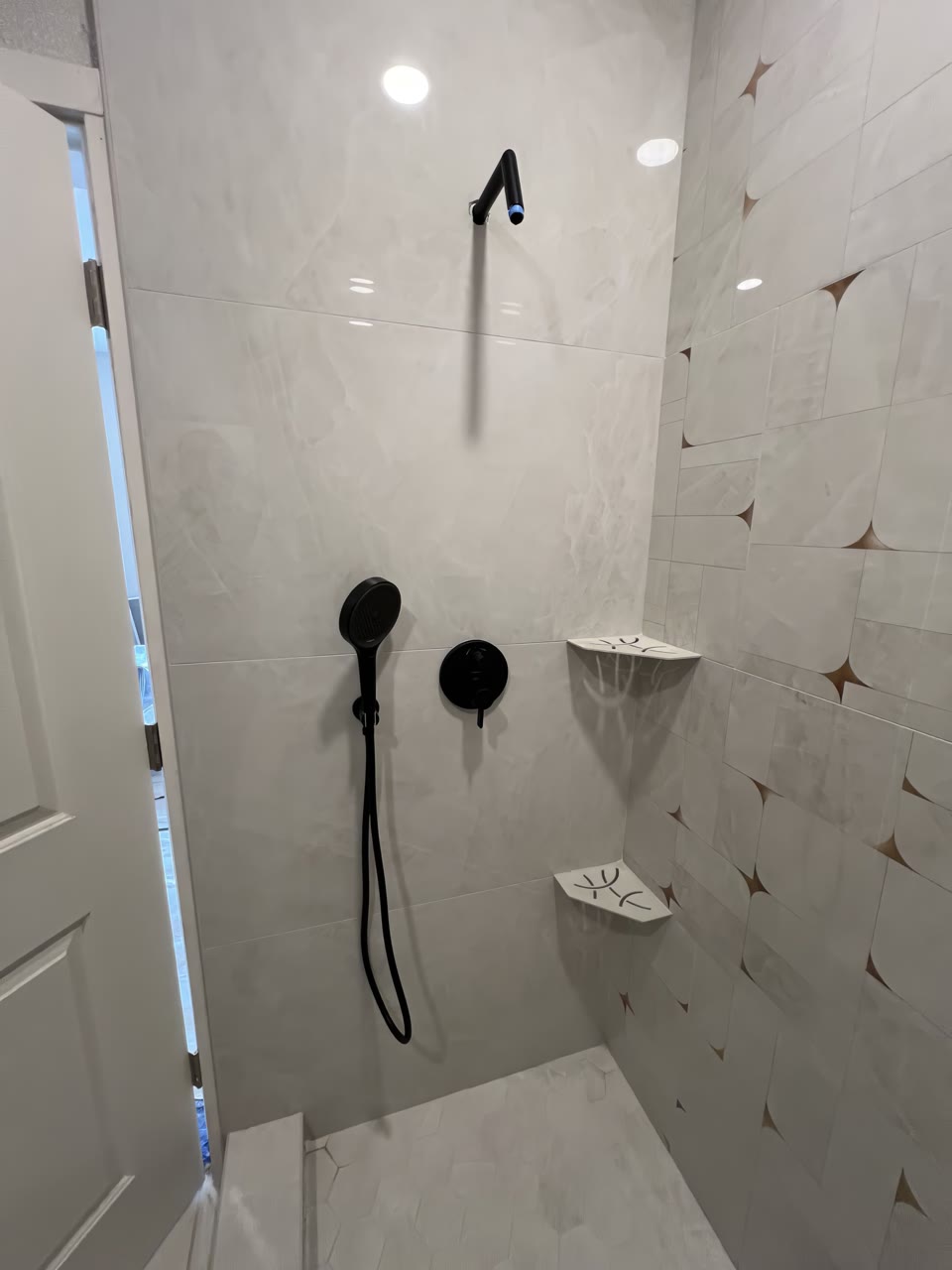 Finished shower with large-format tile, corner shelves and matte black fixtures